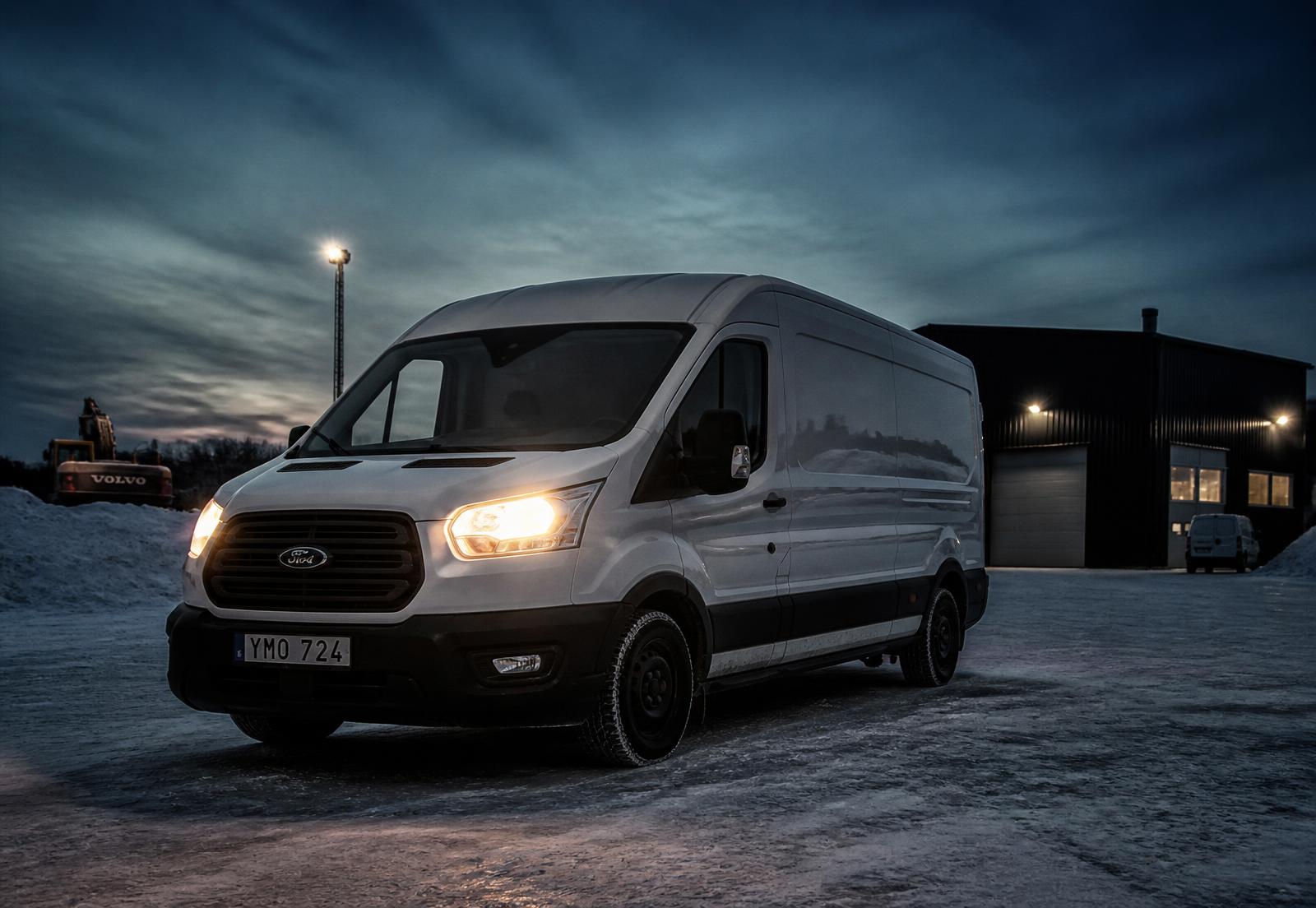 Vit transportbil på snöig industrigård